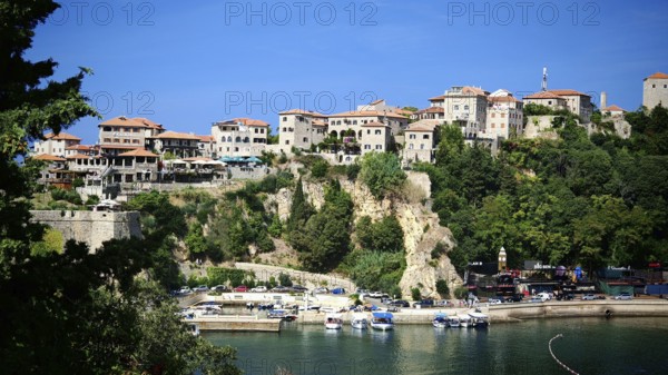 Medieval town on cliff with blue sky and harbor with boats, view of Ulcinj, Montenegro
