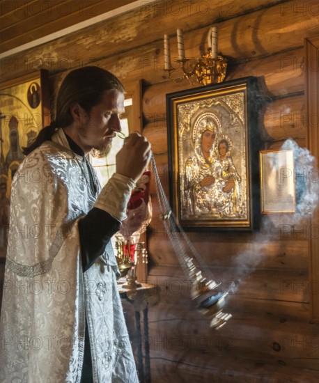 Yuzhno Sakhalin, Sakhalin, Russia. A Russian Orthodox priest during a religious ceremony in a traditionally built wooden Orthodox Church