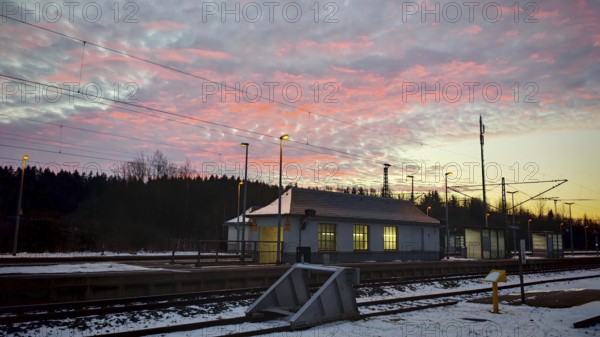 A small train station at dawn under a colorful sky with snow-covered ground, Rennsteig, Frankenwald nature park Park