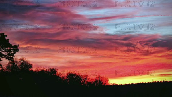 A dramatic sunset with bright, colorful clouds and silhouettes of nature, Frankenwald nature park Park