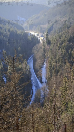View of a winding road in the valley surrounded by wooded hills, Franconian Forest nature park Park