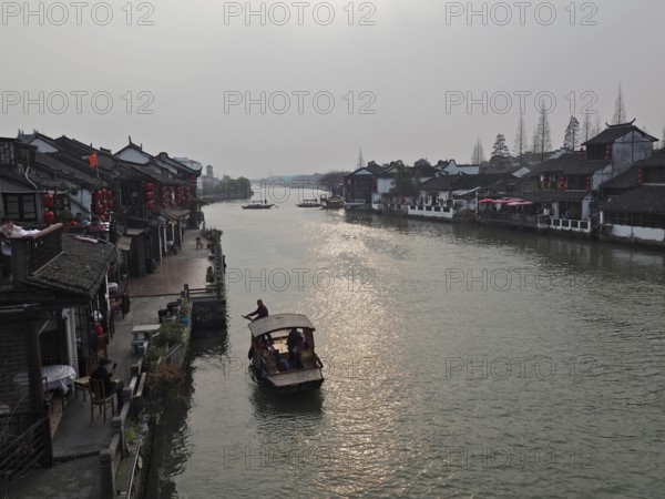 A leisurely evening view across the canal with traditional buildings and boat traffic, Zhujiajiao Ancient Town, Shanghai, China