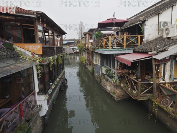 Charming rustic buildings with plants and wood elements along a quiet canal, Zhujiajiao Ancient Town, Shanghai, China