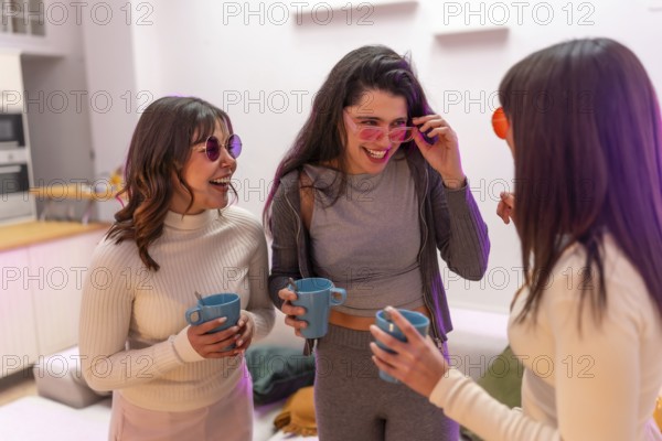 Three young women laughing and chatting at a cozy house party, holding drinks and enjoying a relaxed, vibrant girls night in with warm light and genuine smiles