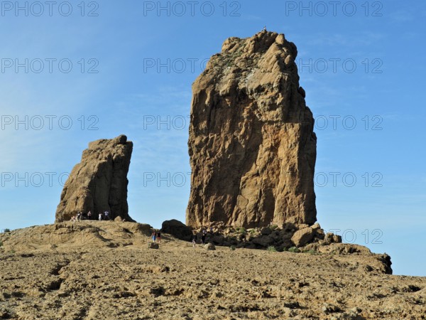 Two huge rock formations under a blue sky with people in the distance, Roque Nublo, Gran Canaria, Canary Islands, Spain