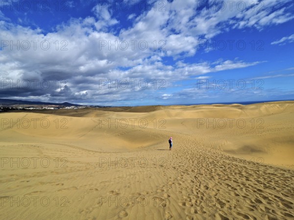 Large dune landscape with footprints and a hiker under a blue sky with white clouds, dunes of Maspalomas, Gran Canaria, Canary Islands, Canary Islands, Spain