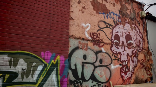 Colourful graffiti on an old wall with a skull motif and various lettering in an urban environment, Tirana, Albania