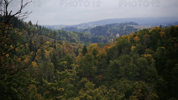 Wide view of wooded hills in autumn under a cloudy sky, Frankenwald nature park Park