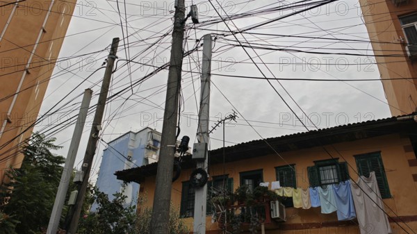 Power poles with a tangle of wires, next to buildings and clotheslines, create an urban image, Tirana, Albania