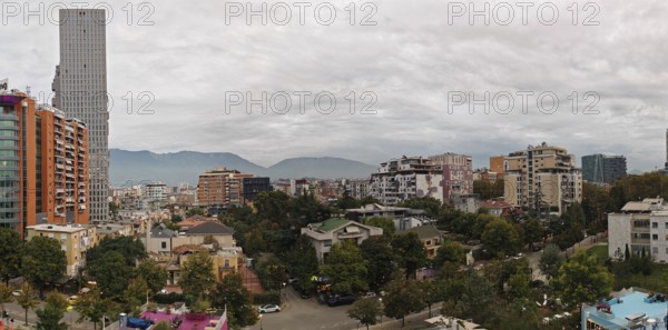Urban panorama with modern high-rise buildings and mountains in the background on a cloudy day. Tirana, Albania