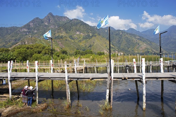 Guatemalan people wearing traditional clothing on a wooden pier in the port of San Juan la Laguna, Atitlán, Sololá Department, Guatemala