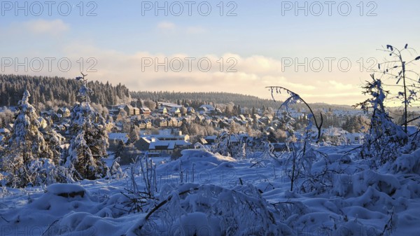 Winter village in snowy landscape with hills and forests in the evening light, Rennsteig, Thuringian Forest nature park Park