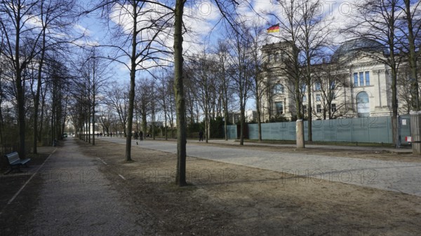 Promenade along the Reichstag with trees and sidewalk on a sunny day, deserted, without people, during corona, Berlin