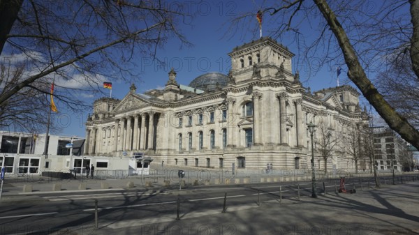 Side view of the Reichstag with flags under a blue sky, deserted during Corona, Berlin