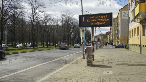 Empty street with digital sign warning of contacts in times of corona, Berlin
