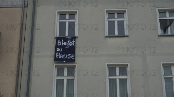 House façade with lettering stays at home during corona on a banner between windows, Berlin