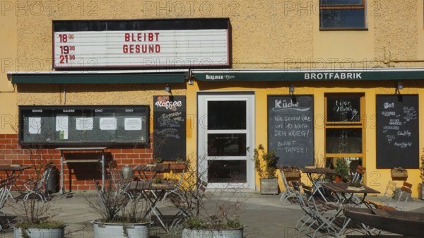 Small café with outdoor seating area and menu boards when the sun is shining with stays healthy and sayings during corona in Berlin, Berlin