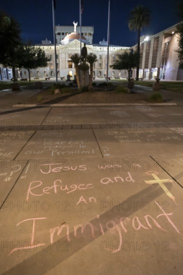 Phoenix, Arizona - Messages written in chalk on the sidewalk at the Arizona State Capitol during a protest against ICE and immigrant deportations. The messages were washed away the following morning, only steps away from a monument honoring the Bill of Rights' first amendment
