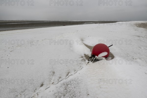 Red buoy on snowy beach, Langeoog, Lower Saxony, Germany