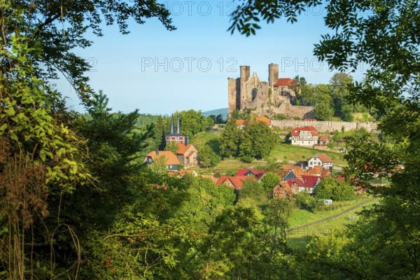 View through the forest of the ruins of Hanstein Castle and the small village of Rimbach, half-timbered houses and village church with half-timbered towers, Bornhagen, Eichsfeld, Thuringia, Germany