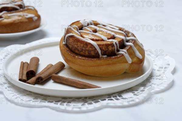 Cinnamon roll on plate and cinnamon sticks