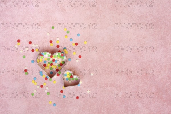 Two heart-shaped baking pans and sugar confetti