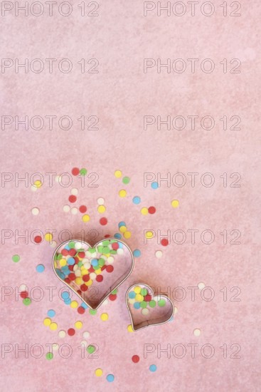 Two heart-shaped baking pans and sugar confetti