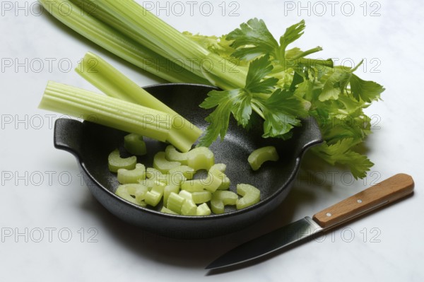 Celery stalks, pieces with knife in pot