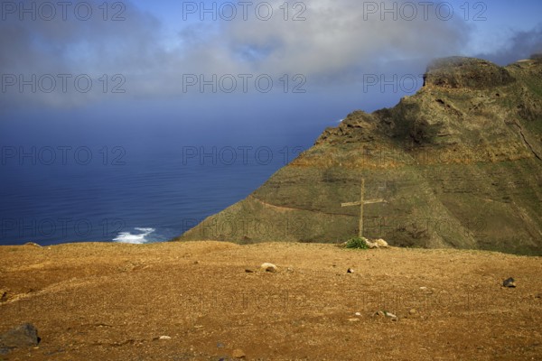 Rocky cliff with a cross in the ground, sea and clouds in the background, Mirador de Ermita de Las Nieves, Lanzarote