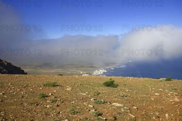 Wide view from Mirador de Ermita de Las Nieves of the coastal village of Caleta de Famara with clouds in the blue sky, Mirador de Ermita de Las Nieves, Lanzarote