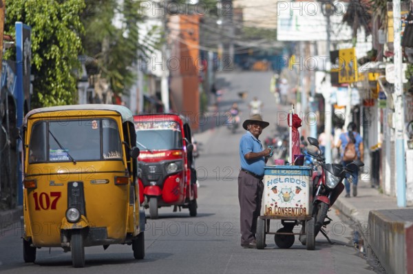 Guatemalan ice cream vendor and tuk tuks or tricycle taxis on a street in Panajachel, Atitlán, Sololá Department, Guatemala