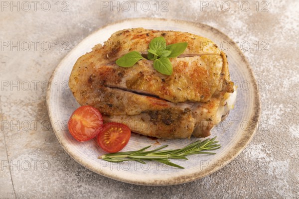 Fried Turkey Thigh with spices and rosemary on plate on brown concrete background. side view, close up