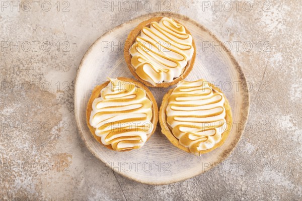 French lemon tart with meringue on brown concrete background, top view, flat lay, close up