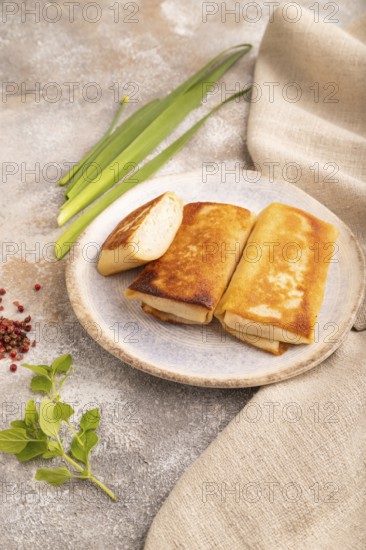 Fried crispy pancakes with meat and cheese on brown concrete background and linen textile. side view, close up