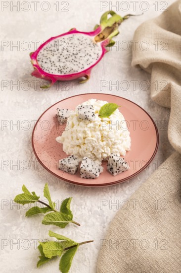 White ?ottage cheese, Curd, with Pithaya on gray concrete background and linen textile, side view, close up