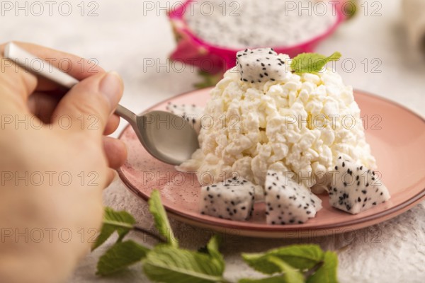 White ?ottage cheese, Curd, with Pithaya with hand on gray concrete background and linen textile, side view, close up, selective focus