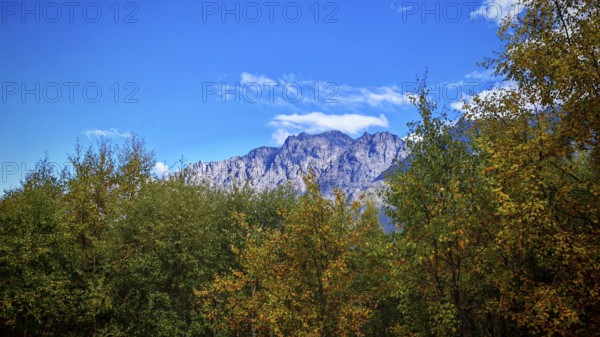 A mountain peak rises majestically above autumn-colored trees, Stepantsminda, Georgia