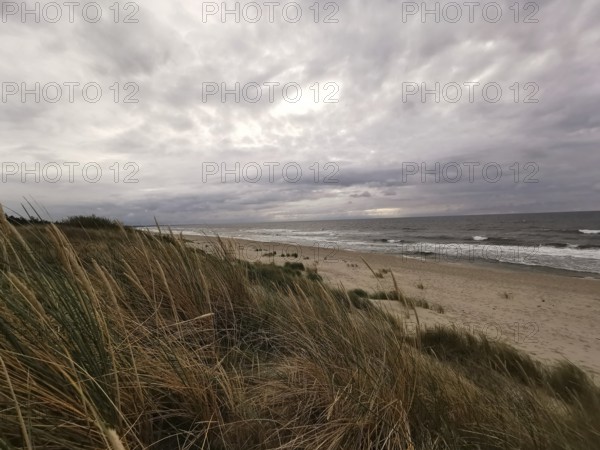 Sandy dunes on the beach with cloudy sky and rough sea in the background, Baltic Sea, fresh spit, Pomerania, Poland