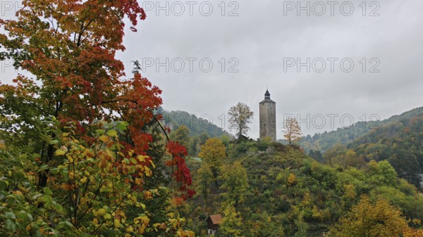 Historic tower on a wooded hill with colorful autumn leaves in a peaceful landscape