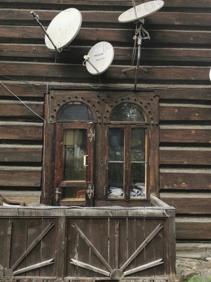 Rustic wooden house with old windows and several satellite dishes, High Tatras, Poland