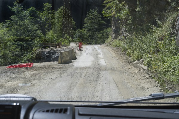 Narrow dirt road leads through wooded mountains, road 7 partly slipped down, west of Mestia, Mingrelia region and Upper Svaneti, High Caucasus, Georgia