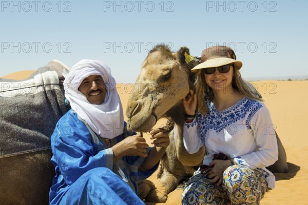 Young woman with Berber and dromedaries in the sand dunes, near Merzouga, Meknès-Tafilalet region, Erg Chebbi, northern Sahara, Morocco