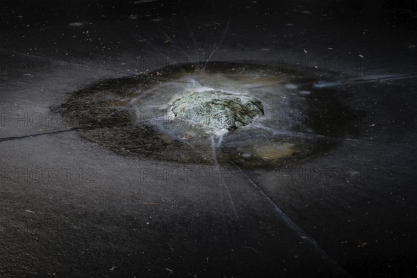 Mossy rock surrounded by cracks in a frozen lake, Finland