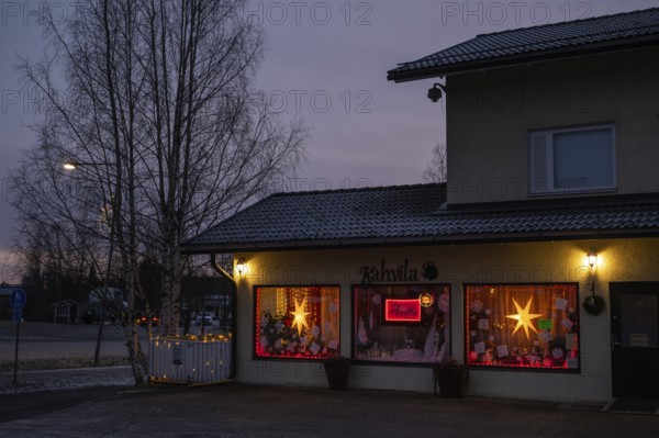 Christmas decorated and illuminated shop window with poinsettias and fairy lights, blue hour, Sysmä, Finland