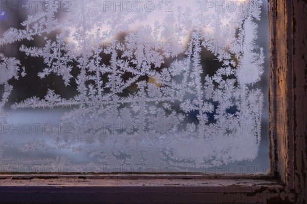 Window with old window frame and frosty ice crystals in the evening light, Finland