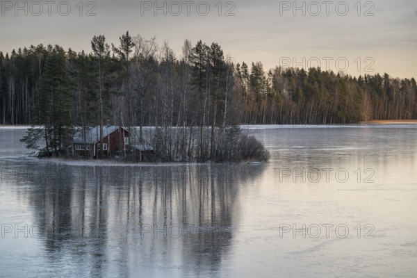 Small island with a red house, frozen lake, edge of forest, winter, Hartola, Finland