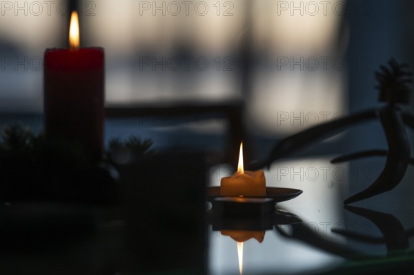 Two candles stand on a table in front of a window at dusk and create a Christmas atmosphere, Finland