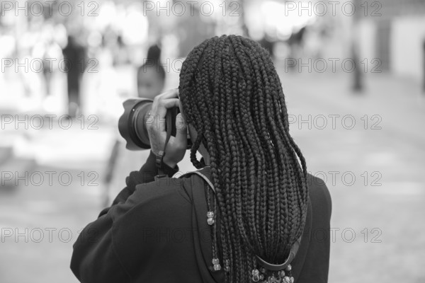 Young girl with black dreadlocks taking pictures, black and white, Paris, France