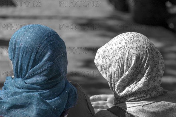 Two woman wearing headscarves talking on a bench, black and white, Paris, France