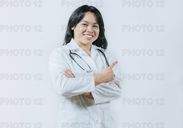 Asian female doctor pointing to the side isolated. Young asian doctor recommending an advertisement